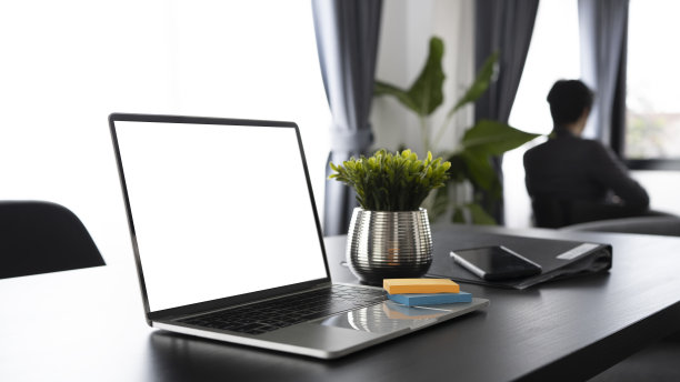 笔记本电脑放在办公桌上，商人坐在后面。图片下载