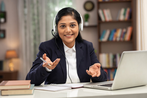 一个商务女性用耳机在家里使用笔记本电脑工作的照片:库存照片图片下载