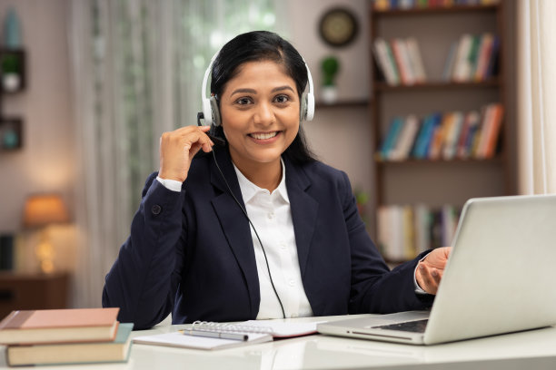 一个商务女性用耳机在家里使用笔记本电脑工作的照片:库存照片图片下载