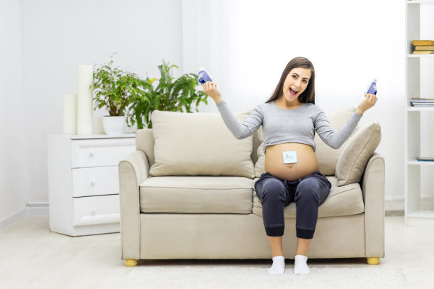 孕妇坐在白色沙发上拿着小鞋的3d插图。图片下载