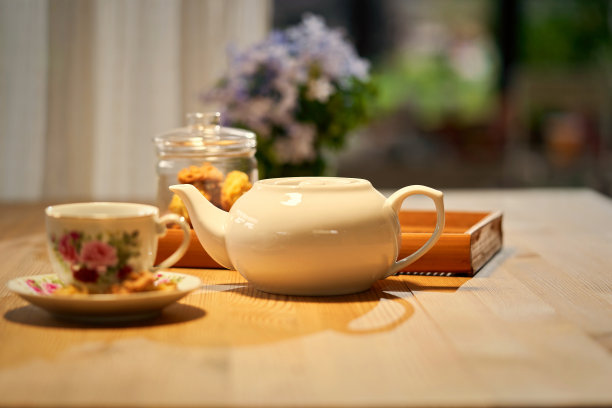 木桌上放着白色的茶壶、杯子和饼干罐图片下载