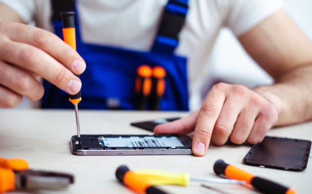 特写照片的专家男子，而他是修理坏了的智能手机在他的工作场所与专业工具图片下载