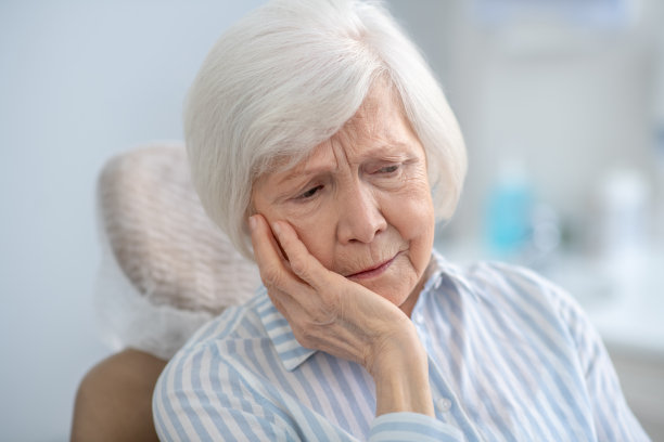 一个灰白头发的女人遭受牙痛的特写图片下载