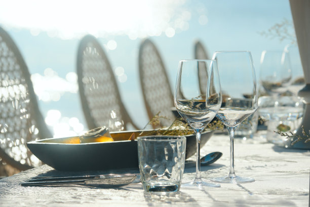 为沙滩上的露天派对做准备。餐桌装饰酒杯和桌子设置在阳光下。图片下载