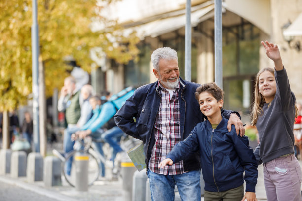一位老人和他的孙儿们站在街上，挥舞着手臂要打一辆出租车。图片下载