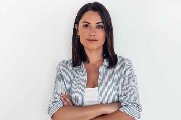 美丽的年轻女子看着相机，而站在客厅在家里。图片下载