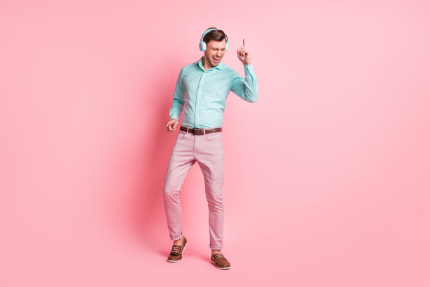 全身照片迷人快乐的男人跳舞戴耳机放松爱音乐孤立在柔和的粉红色背景图片下载