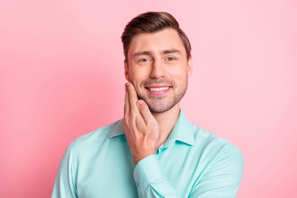 照片肖像的年轻都市美男触摸脸颊刚毛好发型孤立在柔和的粉红色背景图片下载