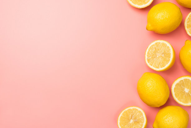 俯视图照片的一半和整个黄色柠檬在右边孤立的淡粉色背景与copyspace在左边图片下载