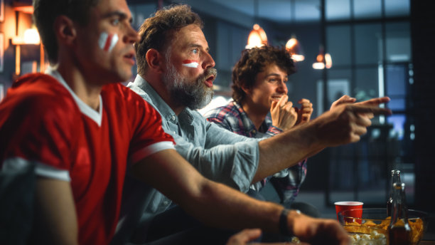 在家里三个快乐的体育迷画着脸坐在沙发上看电视比赛，当运动队赢得冠军时庆祝胜利。朋友欢呼,大喊大叫。特写肖像拍摄图片下载