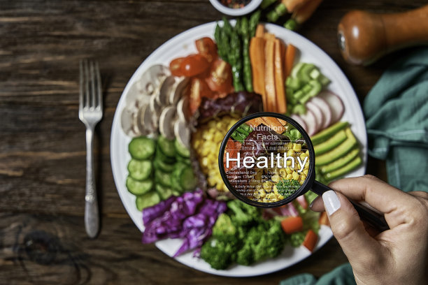 营养信息的概念。女人手拿放大镜显示新鲜素食沙拉的营养成分的实际细节。图片下载