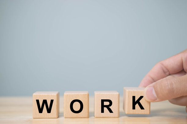 投资者的手把一个写着“工作”的木方块放在木桌上。概念工作在家，计划购买物业。选择最好的。图片下载