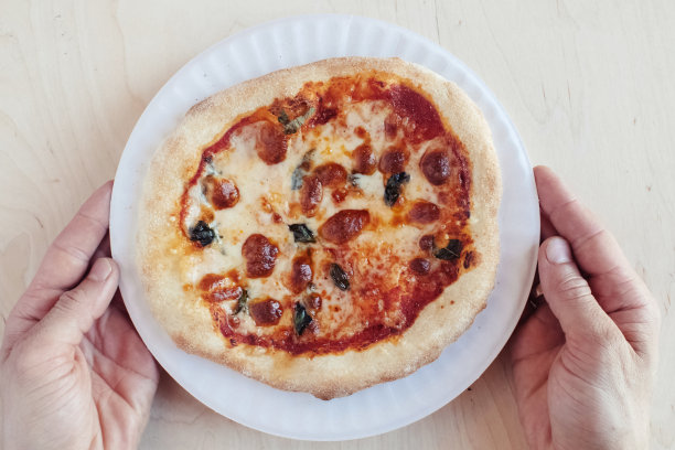 一个在一次性盘子里的迷你披萨的特写镜头。顶视图的外卖食品在快餐店。照片上有马苏里拉奶酪、西红柿、橄榄和各种香肠。一人一餐图片下载