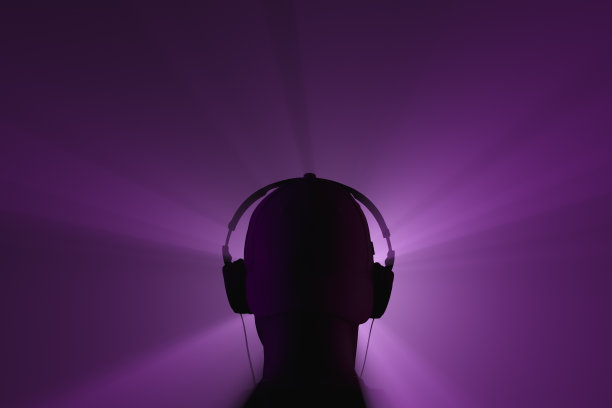 一个戴着耳机的男人的剪影。后视图。聚光灯束图片下载