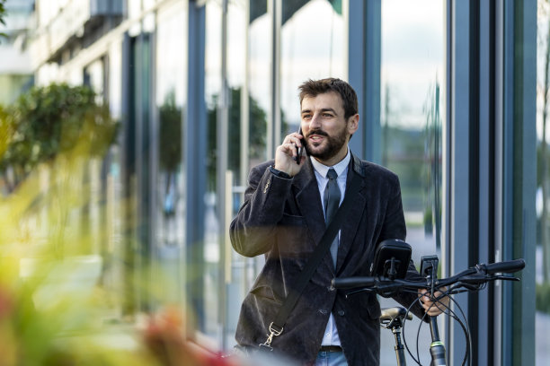 一个商人骑着自行车去办公室，同时正在打电话。图片下载