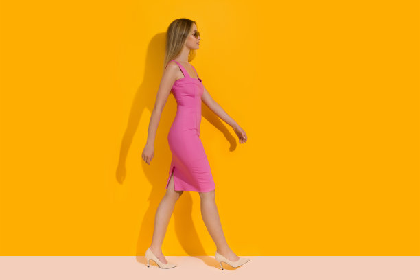 年轻女子穿着粉红色裙子和米色高跟鞋走路图片下载