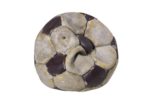 把旧足球踢在白色的桌子上。皮革和破坏球没有空气。光背景。图片下载