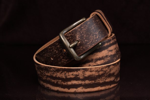棕色皮带与磨损和金属扣在黑暗的背景。图片下载