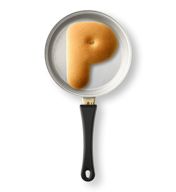 在白色背景上的一个旧玩具煎锅上的大写字母饼干P孤立的镜头图片下载