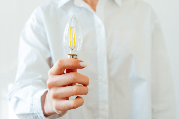 穿白衬衫的女人手里拿着灯泡图片下载