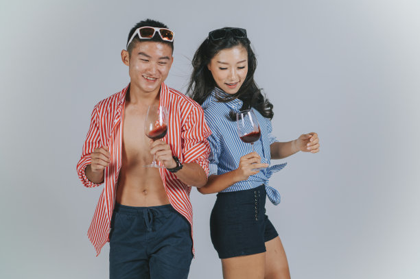时尚的亚洲华人夫妇跳舞与夏天穿拿着酒杯工作室拍摄剪出与灰色背景图片下载