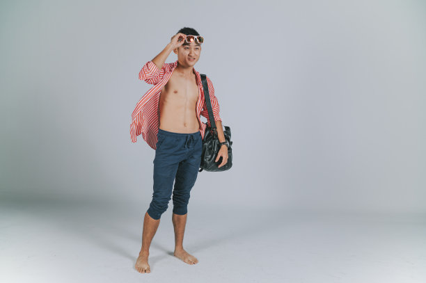 时尚的亚洲华人青年夏天戴着墨镜拎着包拍摄剪出灰色的背景图片下载