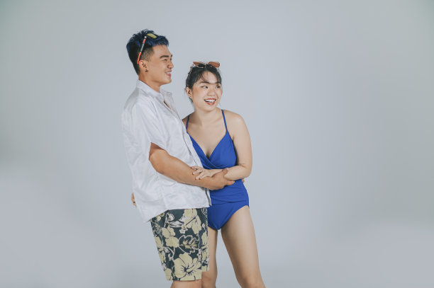 亚洲华人年轻夫妇夏季泳装摄影工作室剪出灰色背景图片下载