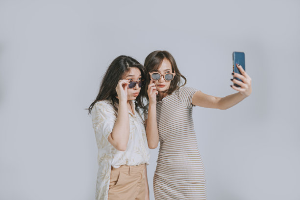 时尚亚洲华人夏装自拍与智能手机工作室拍摄剪出灰色背景图片下载