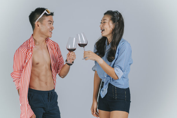 时尚的亚洲华人夫妇跳舞与夏天穿拿着酒杯工作室拍摄剪出与灰色背景图片下载