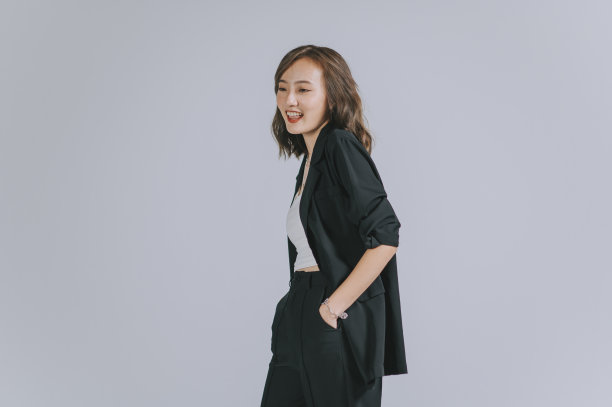 亚洲中国美丽的女人站在口袋微笑与灰色的背景工作室拍摄图片下载