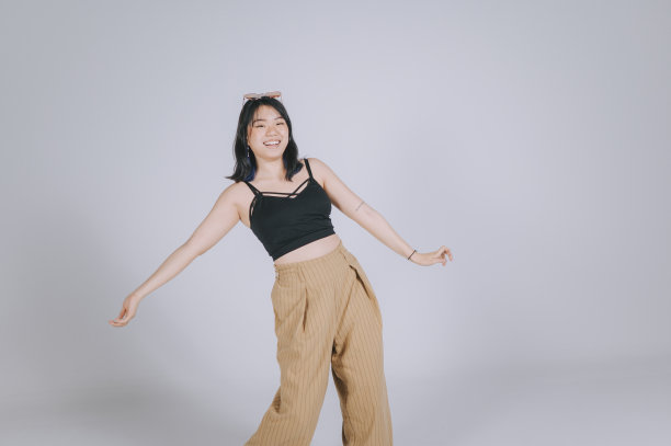 亚洲中国少女跳舞在工作室拍摄与灰色背景的乐趣图片下载