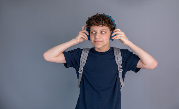 十几岁的男孩是学生，背着背包，戴着耳机图片下载