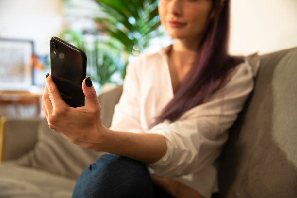 年轻女性拿着并使用智能手机图片下载