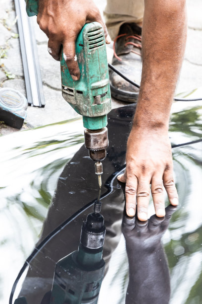 工人用螺钉将屋顶聚碳酸酯板穿入结构框架图片下载