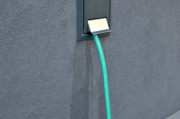 在立面的墙上有一个带水龙头的橱柜，叫做“露营者”。软管被连接并从孔中流出。门会锁上的图片下载