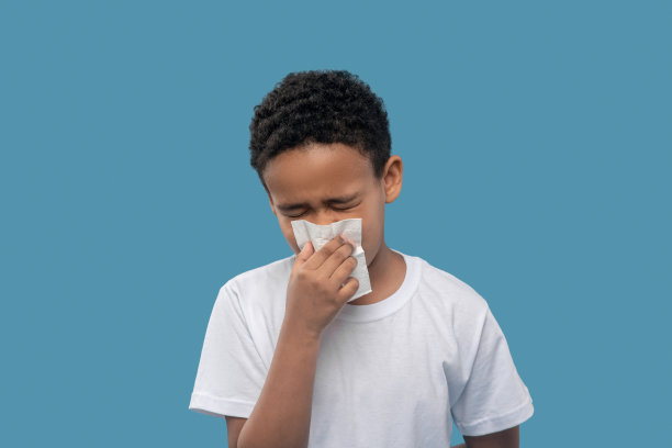 闭着眼睛，把餐巾放在鼻子旁边的男孩图片下载