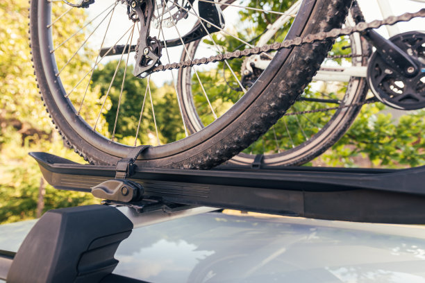 自行车安装在车顶自行车架上的银色汽车上，背景是乡村风景图片下载