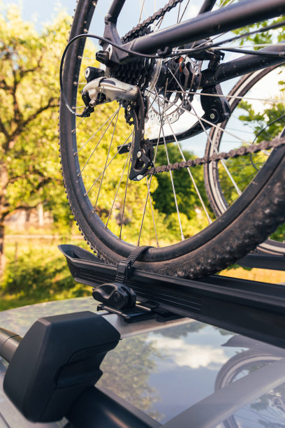 自行车安装在车顶自行车架上的银色汽车上，背景是乡村风景图片下载