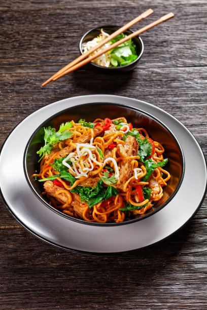 烤豆肉条配辣蛋面、豆芽、羽衣甘蓝、香菜和辣椒放在一个木桌上，亚洲美食，垂直视角图片下载