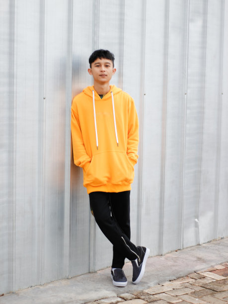 一名穿着连帽衫的东南亚男子靠在墙上图片下载