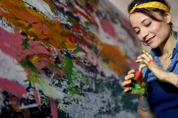 放松的年轻女子画家正在创作一幅大型现代抽象油画，用手指在画布上涂抹颜料图片下载