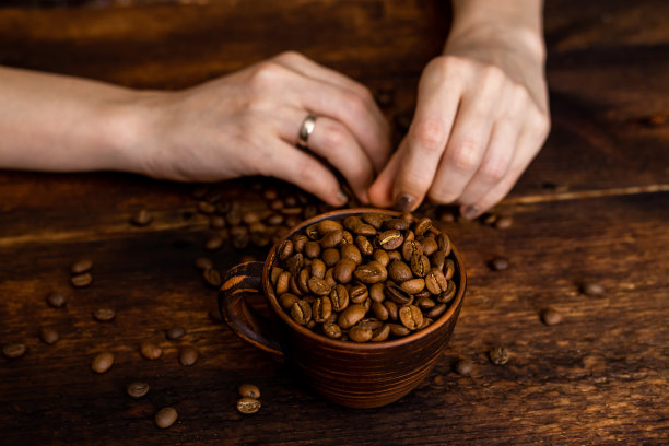 咖啡满杯和女性的手在棕色的老木头背景。图片下载