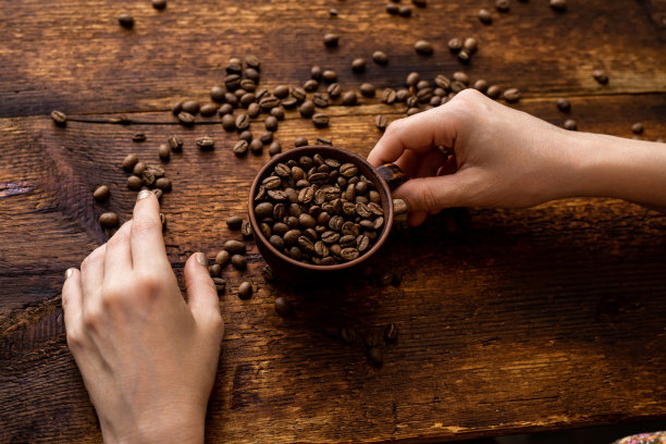 咖啡满杯和女性的手在棕色的老木头背景。图片下载