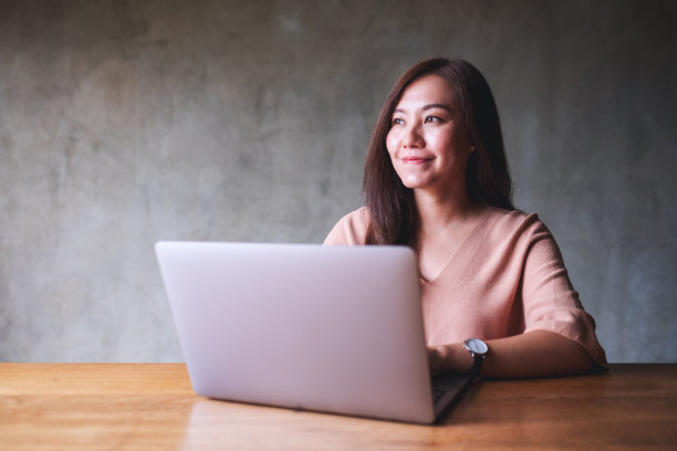 一个美丽的年轻亚洲女人使用和工作在笔记本电脑图片下载