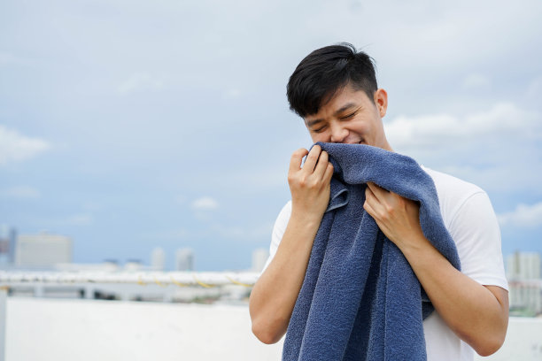 近距离观察年轻的亚洲男子闻完浴巾后，从家里花园户外晾干衣服，为日常和例行的生活方式概念图片下载