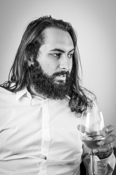 手持一杯新鲜白葡萄酒的中东年轻商人肖像图片下载