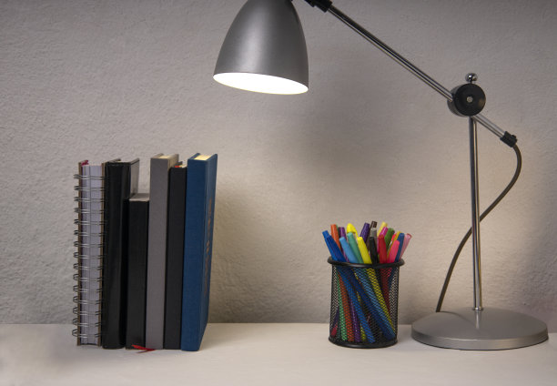 学生工作场所和书，笔筒，灯靠在白色的墙上。晚上做家庭作业图片下载