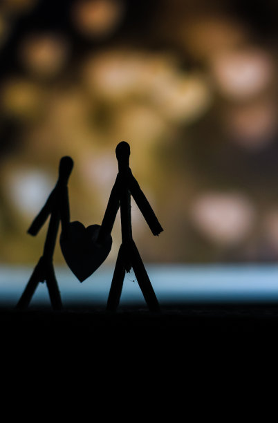 爱的夫妻用火柴棍的概念。男性和女性靠在一起，背景是美丽的心形。火柴艺术摄影用火柴棒创造了这个人物。图片下载