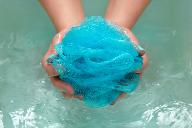 女用手捧着一条圆形柔软的合成毛巾在水中沐浴。手的特写镜头。水疗，身体护理，水背景图片下载