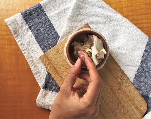 用木板、油、盐和有纹理的厨房毛巾手工采摘蒜瓣图片下载